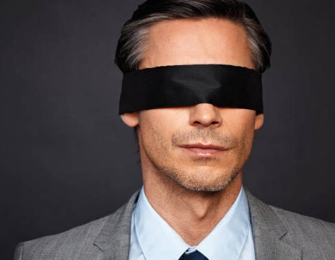 Closeup of man in suit and tie wearing blindfold
